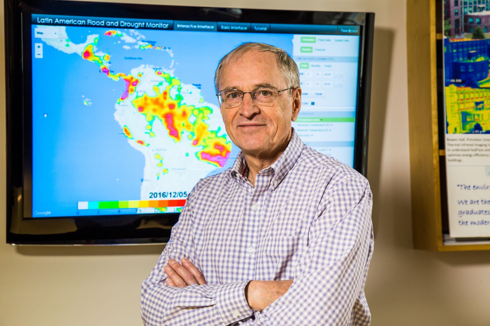Eric Wood, standing, hands crossed, in front of a colorful computer-generated map of South America